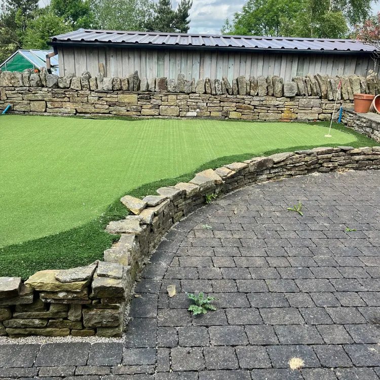 Block paving beside a putting green before pressure washing, black with grime